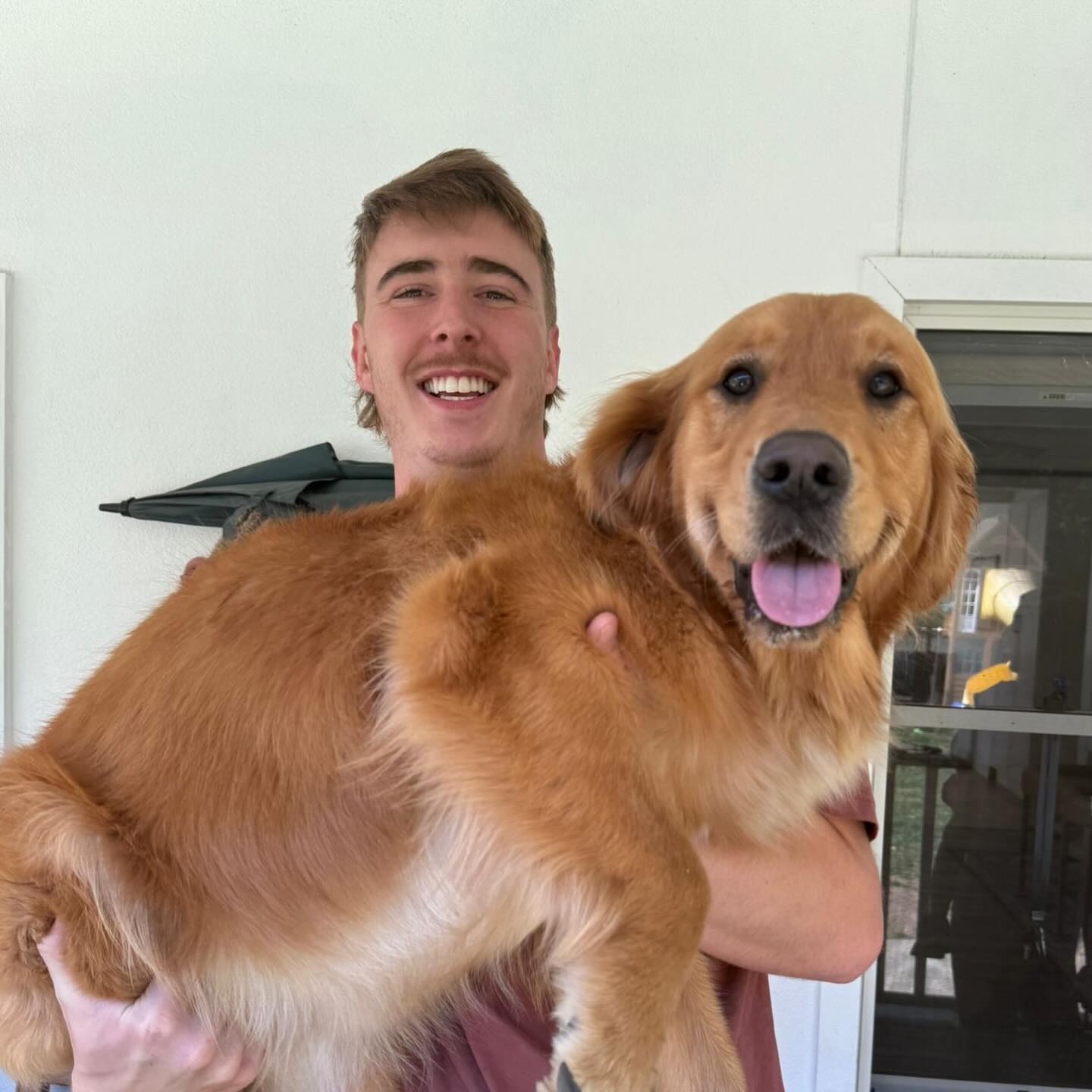 Quinn smiling while holding a golden retriever
